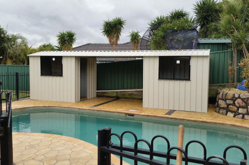 Garden Sheds - Larger cream coloured shed next to a pool by New Look Shed City